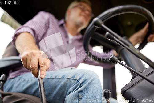 Image of senior man driving tractor at farm