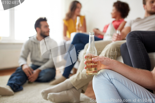 Image of close up of man with beer bottle and friends