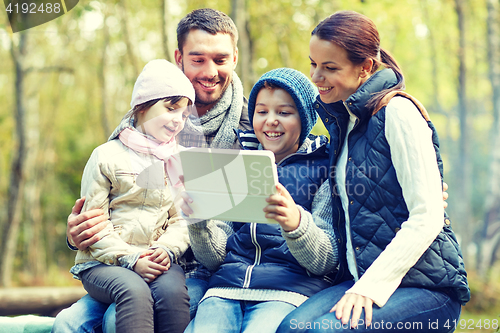 Image of family sitting on bench with tablet pc at camp