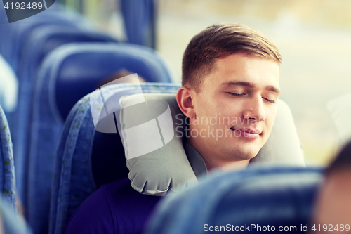 Image of happy young man sleeping in travel bus with pillow