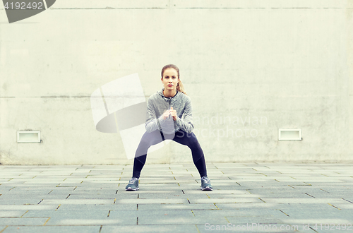 Image of woman doing squats and exercising outdoors