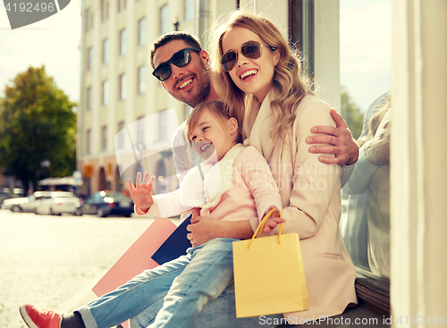 Image of happy family with child and shopping bags in city