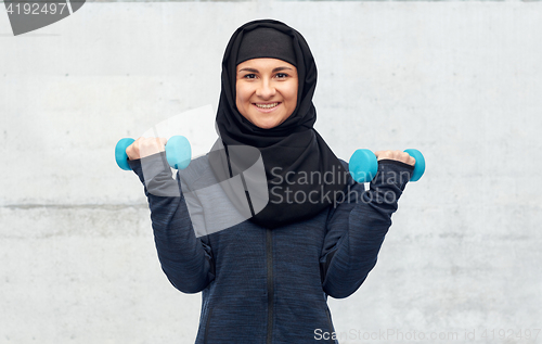 Image of muslim woman in hijab with dumbbells doing fitness