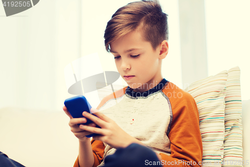 Image of boy with smartphone texting or playing at home