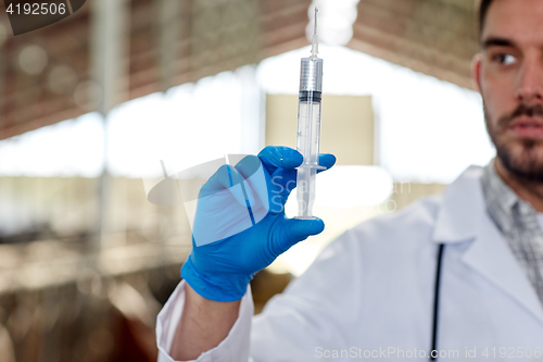 Image of veterinarian hand with vaccine in syringe on farm