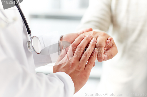 Image of close up of doctor holding old man hand