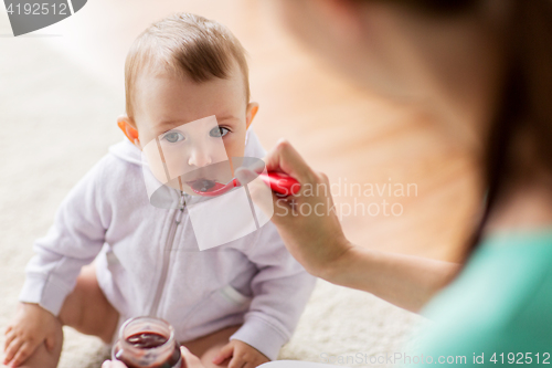 Image of mother with spoon feeding little baby at home