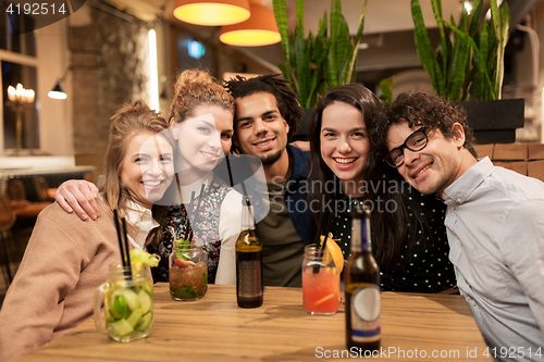 Image of happy friends with drinks at bar or cafe