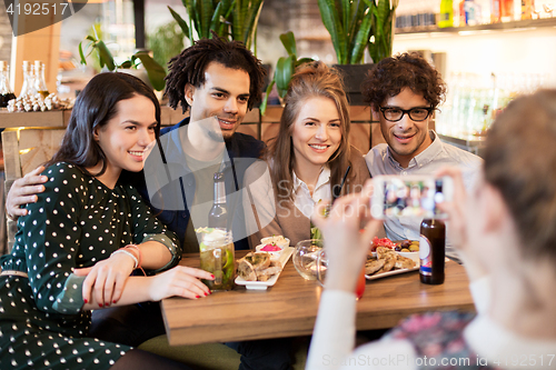 Image of friends with smartphone photographing at cafe