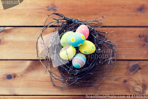 Image of close up of colored easter eggs in nest on wood