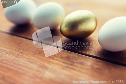 Image of close up of golden and white easter eggs on wood