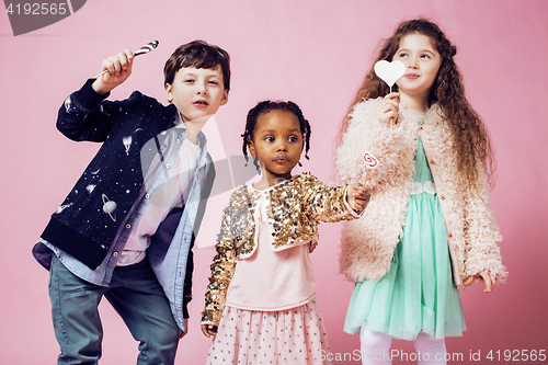 Image of lifestyle people concept: diverse nation children playing together, caucasian boy with african little girl holding candy happy smiling 