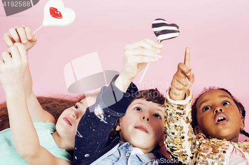 Image of lifestyle people concept: diverse nation children playing together, caucasian boy with african little girl holding candy happy smiling 