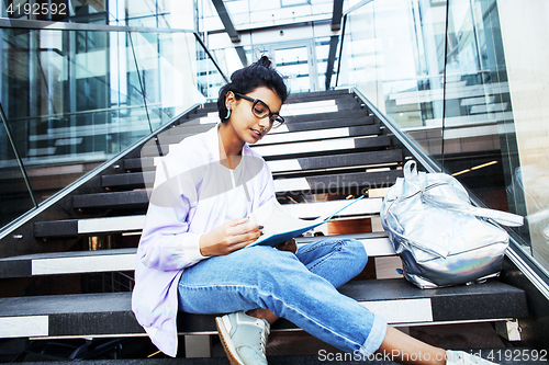 Image of young cute indian girl at university building sitting on stairs 