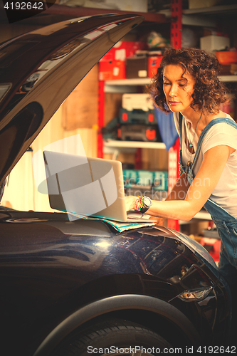 Image of Beautiful woman mechanic near a car