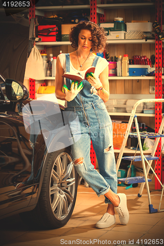 Image of car mechanic, a beautiful woman studying the instructions for re