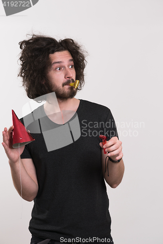 Image of Portrait of a man in party hat blowing in whistle