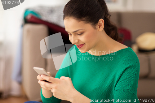 Image of happy woman with smartphone at home