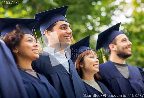 Image of happy students or bachelors in mortar boards