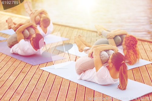 Image of group of people making yoga exercises outdoors