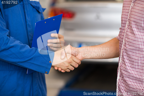 Image of auto mechanic and man shaking hands at car shop