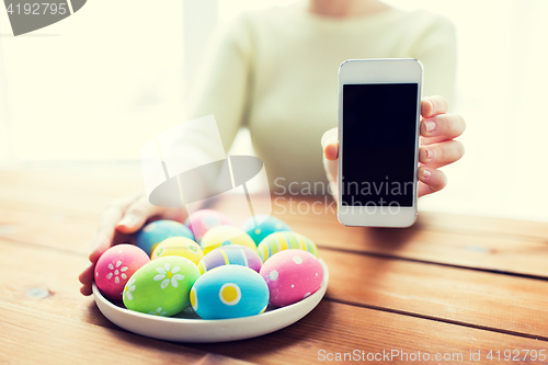 Image of close up of hands with easter eggs and smartphone