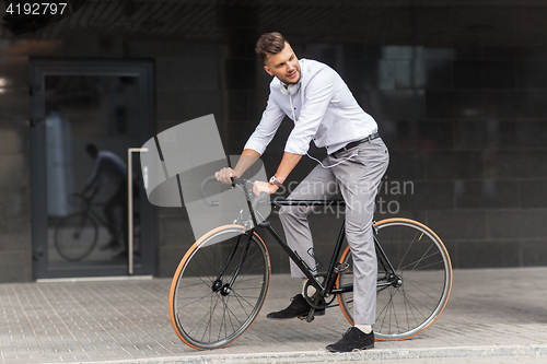 Image of man with bicycle and headphones on city street