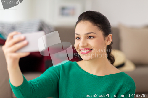 Image of happy young woman taking selfie with smartphone