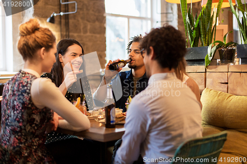 Image of happy friends eating and drinking at bar or cafe