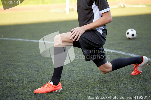 Image of soccer player stretching leg on field football