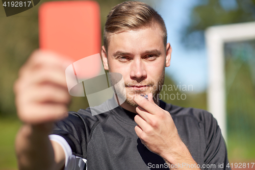 Image of referee on football field showing red card