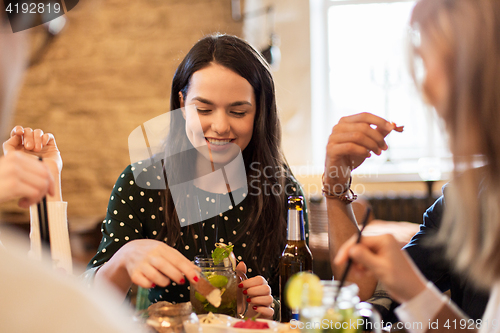 Image of happy friends eating and drinking at bar or cafe