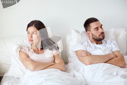 Image of unhappy couple having conflict in bed at home