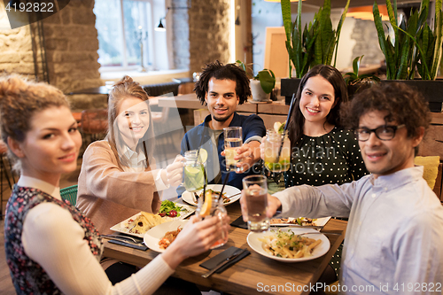 Image of happy friends with drinks and food at restaurant