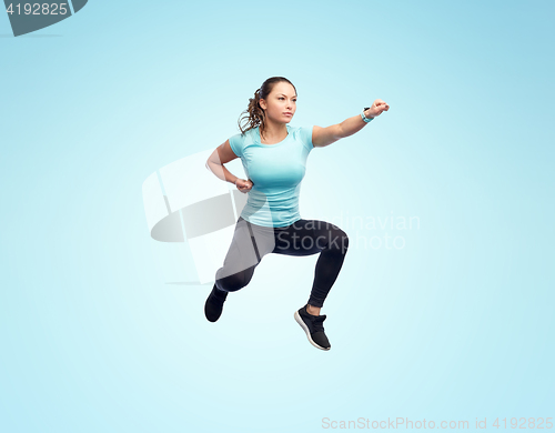 Image of happy sporty young woman jumping in fighting pose