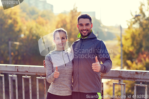 Image of smiling couple showing thumbs up outdoors