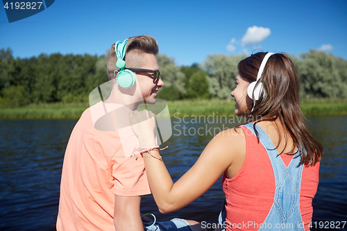 Image of teenage couple with headphones on river berth