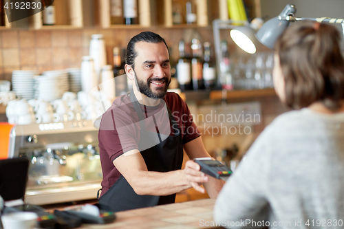 Image of man or waiter with card reader and customer at bar