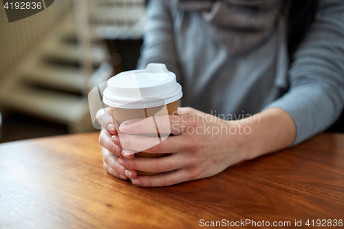 Image of smiling young woman drinking coffee at cafe