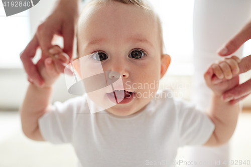 Image of happy baby learning to walk with mother help