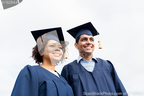 Image of happy students or bachelors in mortarboards