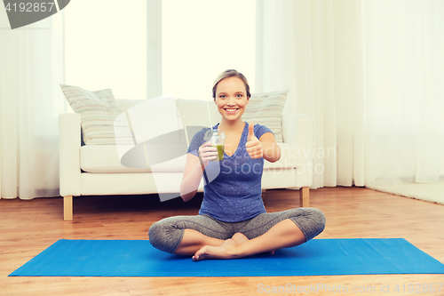 Image of woman with smoothie showing thumbs up at home