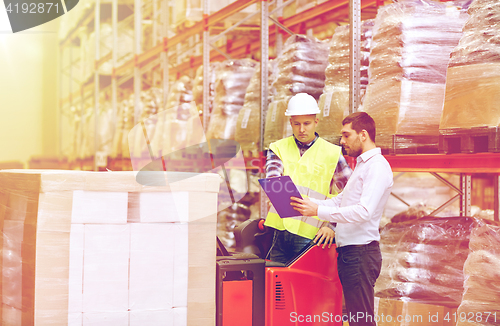 Image of worker and businessmen with clipboard at warehouse