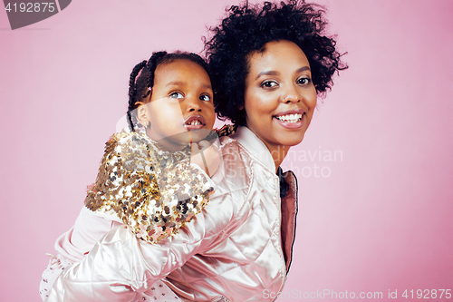 Image of young pretty african-american mother with little cute daughter hugging, happy smiling on pink background, lifestyle modern people concept 