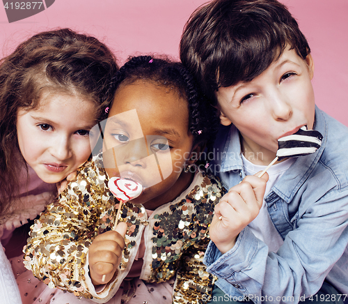 Image of lifestyle people concept: diverse nation children playing together, caucasian boy with african little girl holding candy happy smiling 