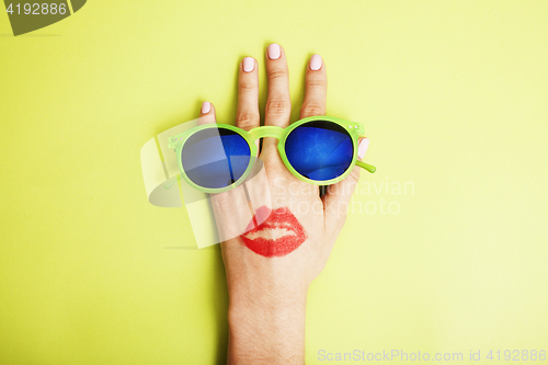 Image of woman hand holding sunglasses on bright background, cosmetic summer vacation concept