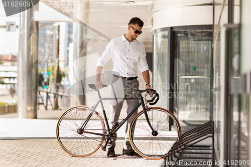 Image of young man parking his bicycle on city street