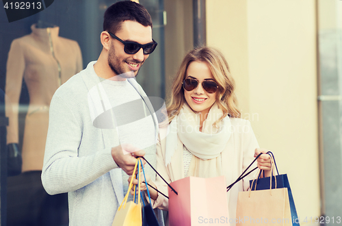 Image of happy couple with shopping bags at shop window