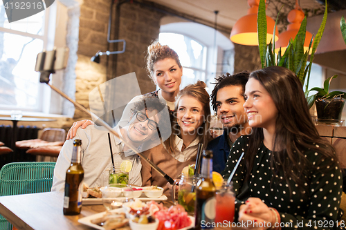 Image of friends taking selfie by smartphone at bar or cafe