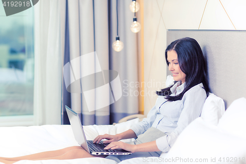 Image of happy businesswoman with laptop in hotel room